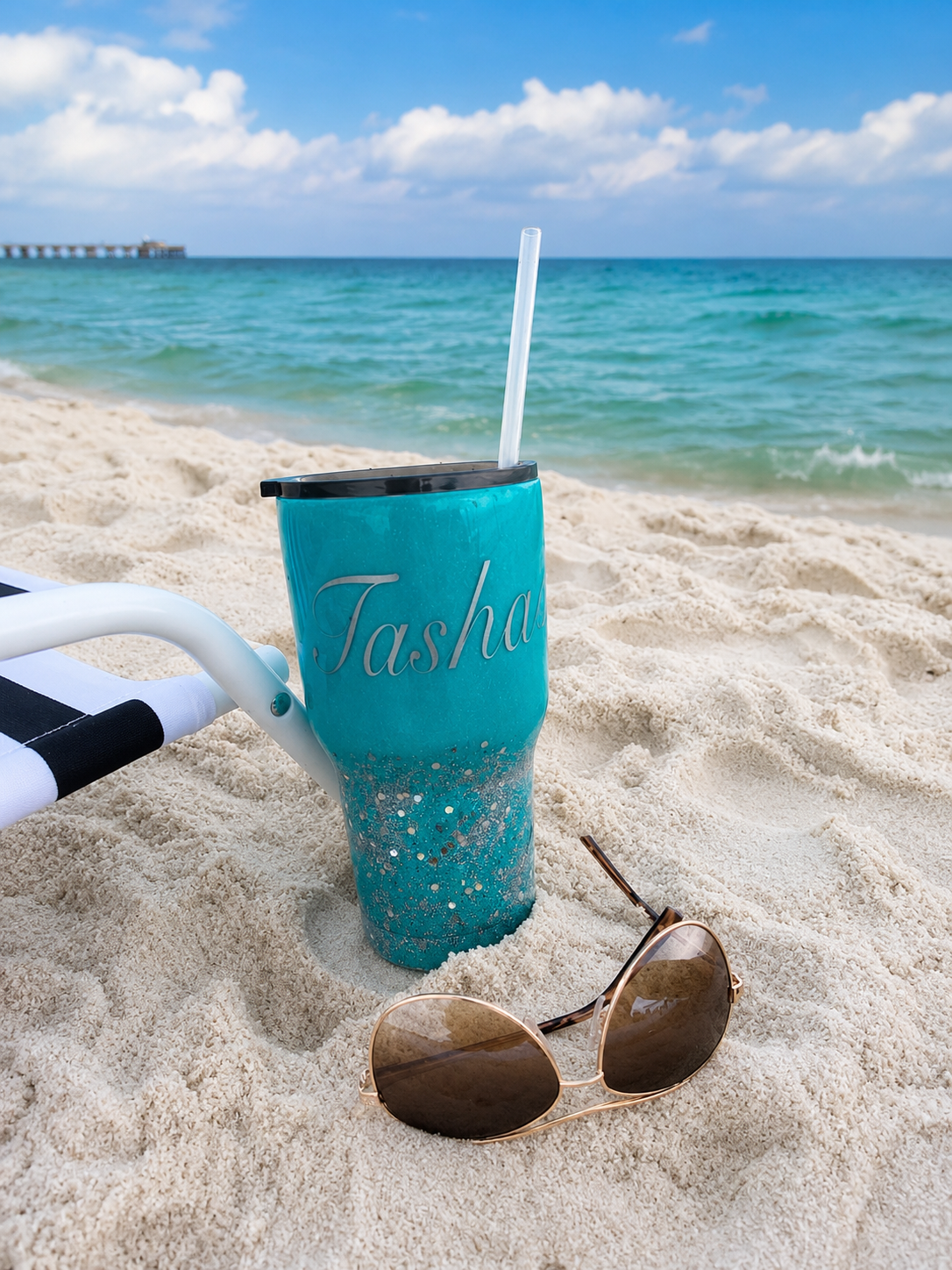 Custom teal glitter tumbler with name 'Tasha' on a sunny beach